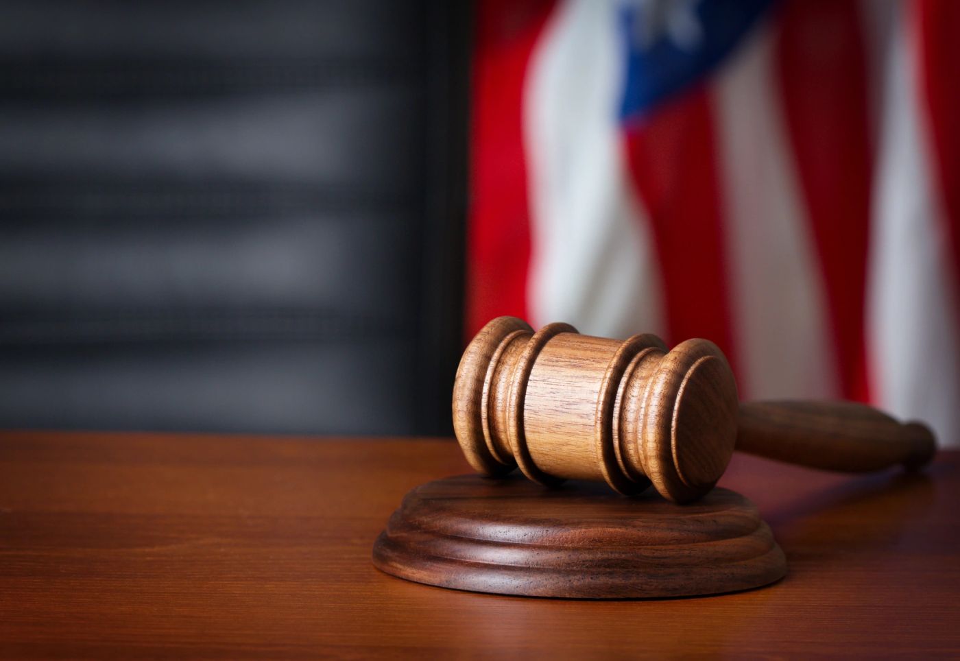 A wooden gavel resting in front of an American flag.