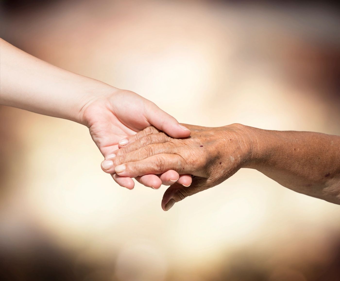 A younger hand and an older hand clasped together in support.