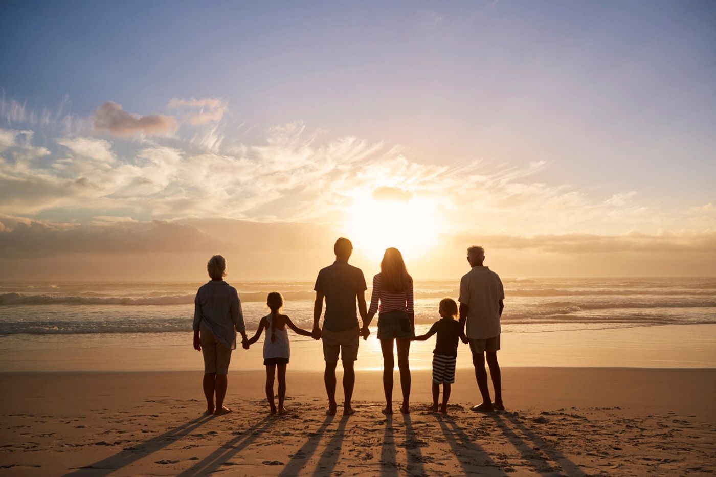 A family walking together along the shore at sunset.